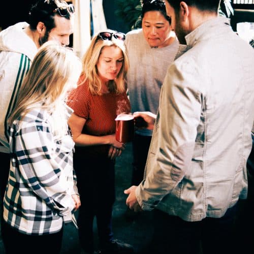 Four coffee enthusiasts looking into a jug of steamed milk that an Iron & Fire barista trainer is holding.