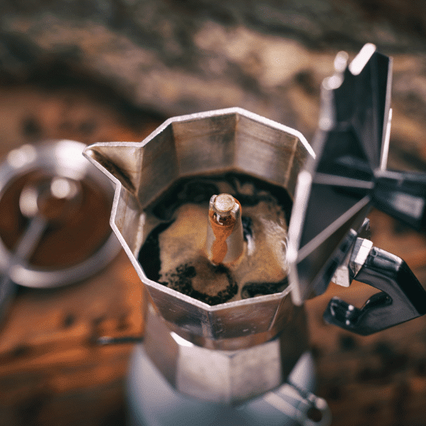 Italian traditional moka pot (coffee maker) with hot coffee flowing out from the spout
