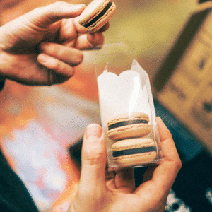 Three coffee-flavoured macarons being held