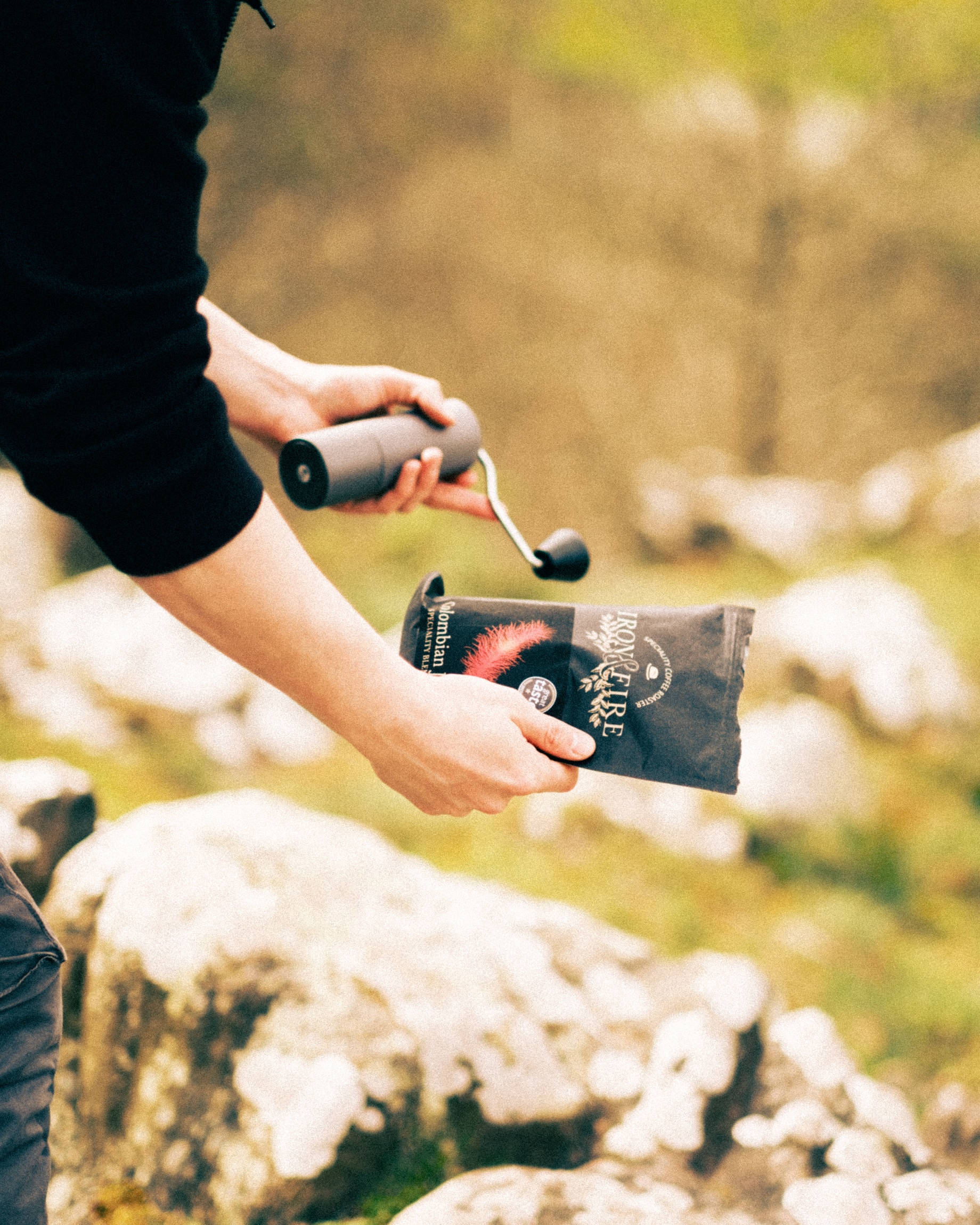 Iron & Fire coffee and a hand grinder with scenery from a Shropshire hill in the background