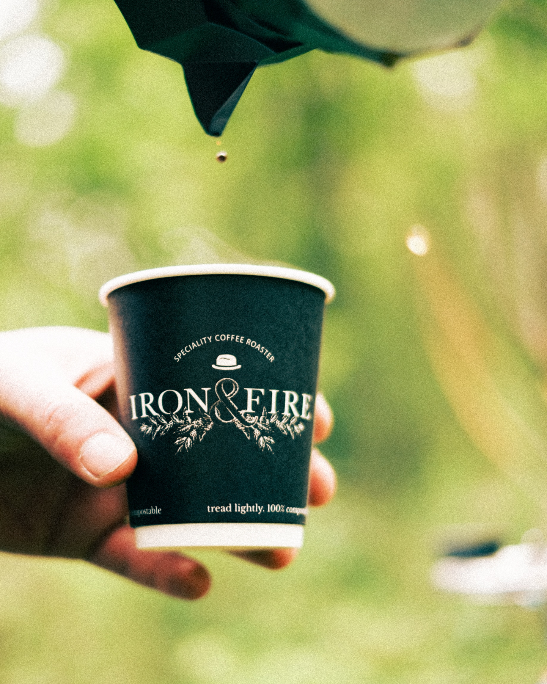 Coffee being poured from a Moka pot into an Iron & Fire cup outdoors