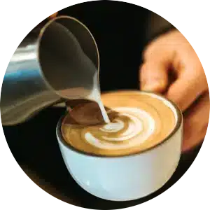 A circular image of a latte being poured.