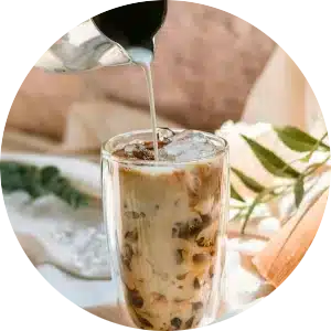 A circular image of an iced latte being poured.