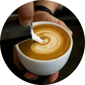 A circular image of a latte being poured.
